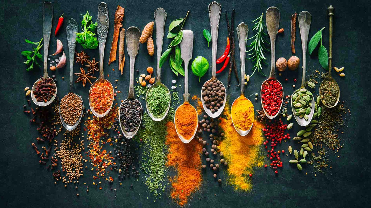 Various colorful spices laid out on table on spoons