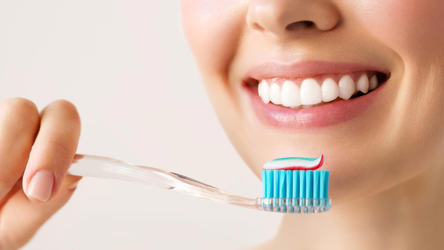 Lady holding toothbrush topped with toothpaste to her mouth