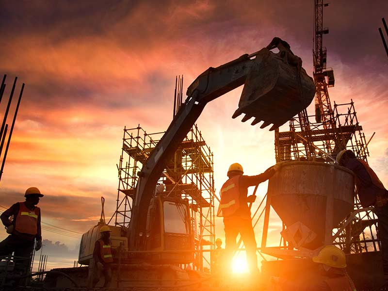construction workers in sunset with construction equipment
