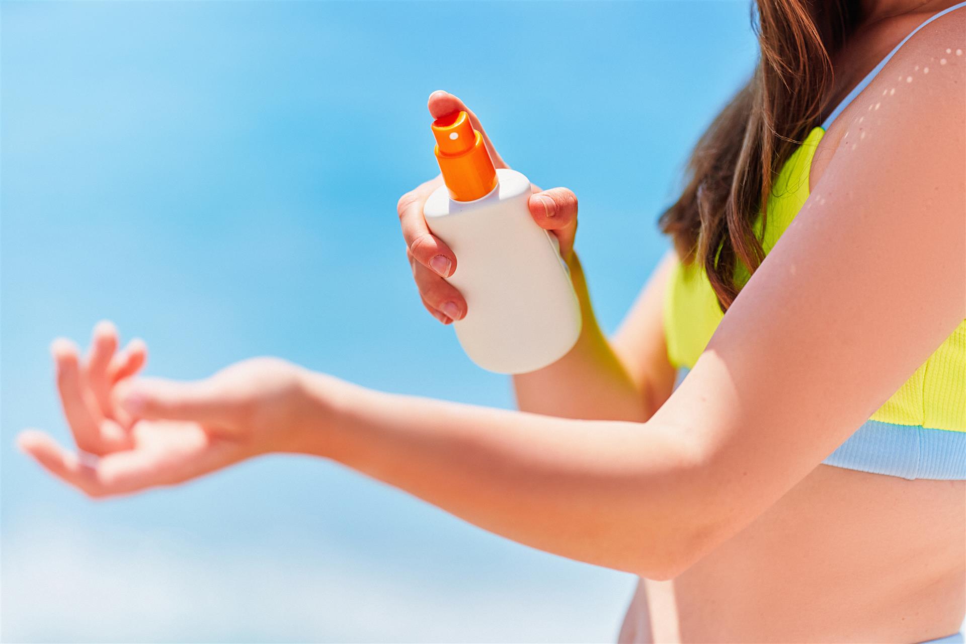 female-applying-holding-white-empty-bottle-blank-sunscreen-lotion-while-sunbathing-beach-by-sea-sunny-summer-day-sun-protection (Custom) Female applying and holding white empty bottle blank of sunscreen lotion while sunbathing on beach by the sea in sunny summer day. Sun protection